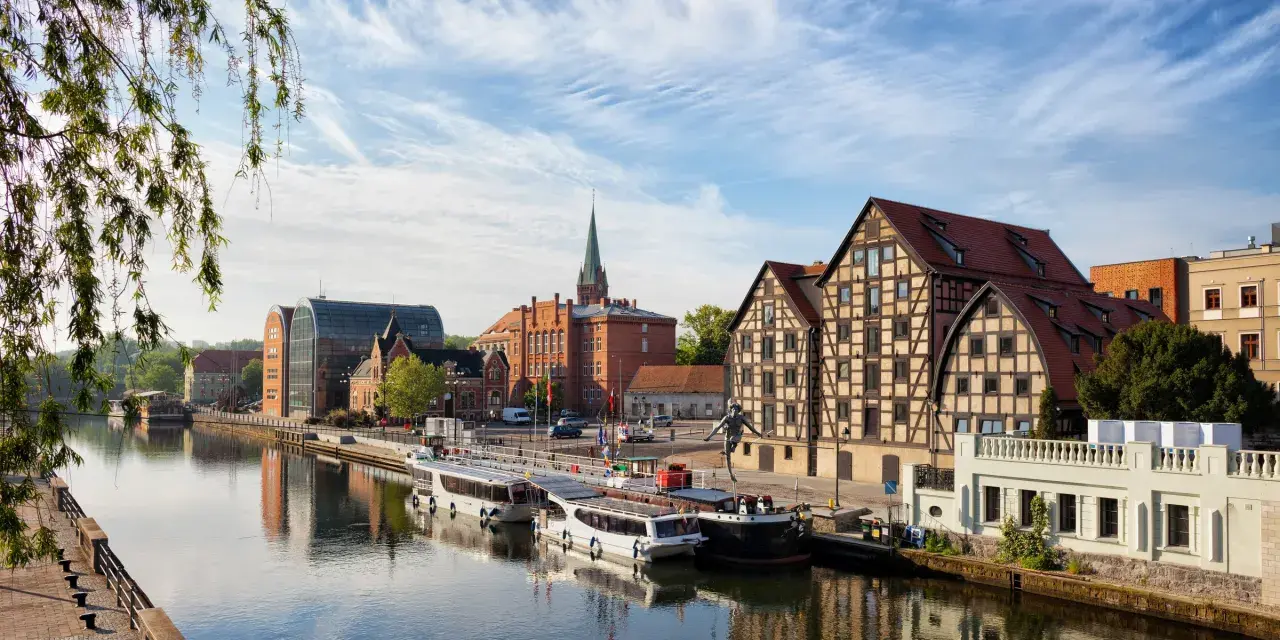 Bydgoszcz: rzeka, statki, zabytkowe kamienice i nowoczesna architektura.