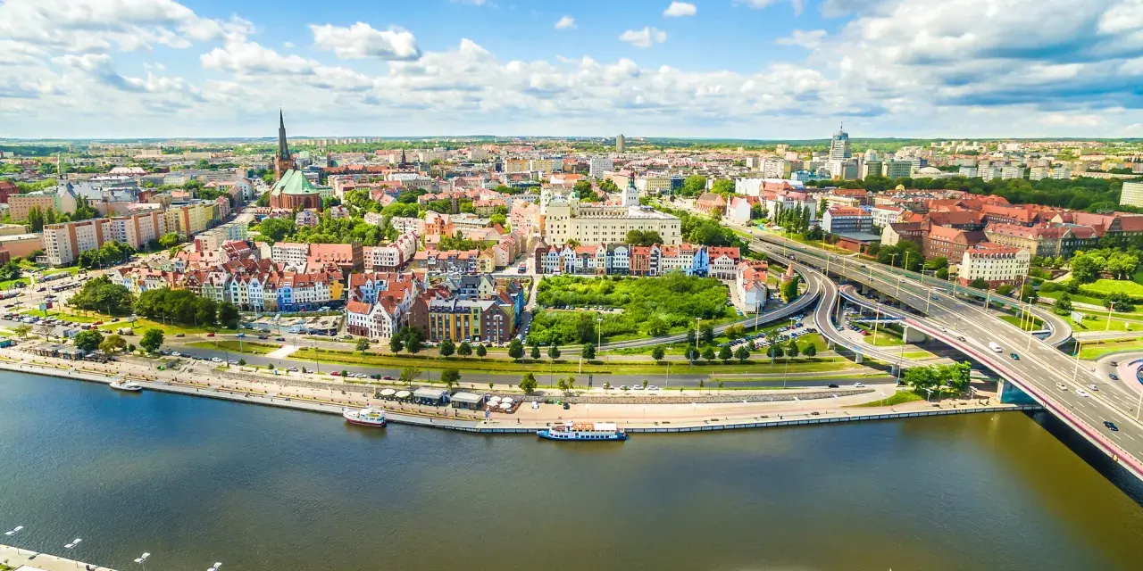 Widok z lotu ptaka na Szczecin z rzeką, nabrzeżem, statkami i mostem.
