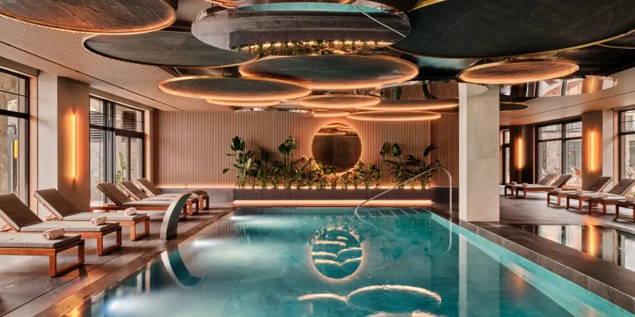 Nowoczesny basen w hotelu SPA z leżakami i roślinnością.