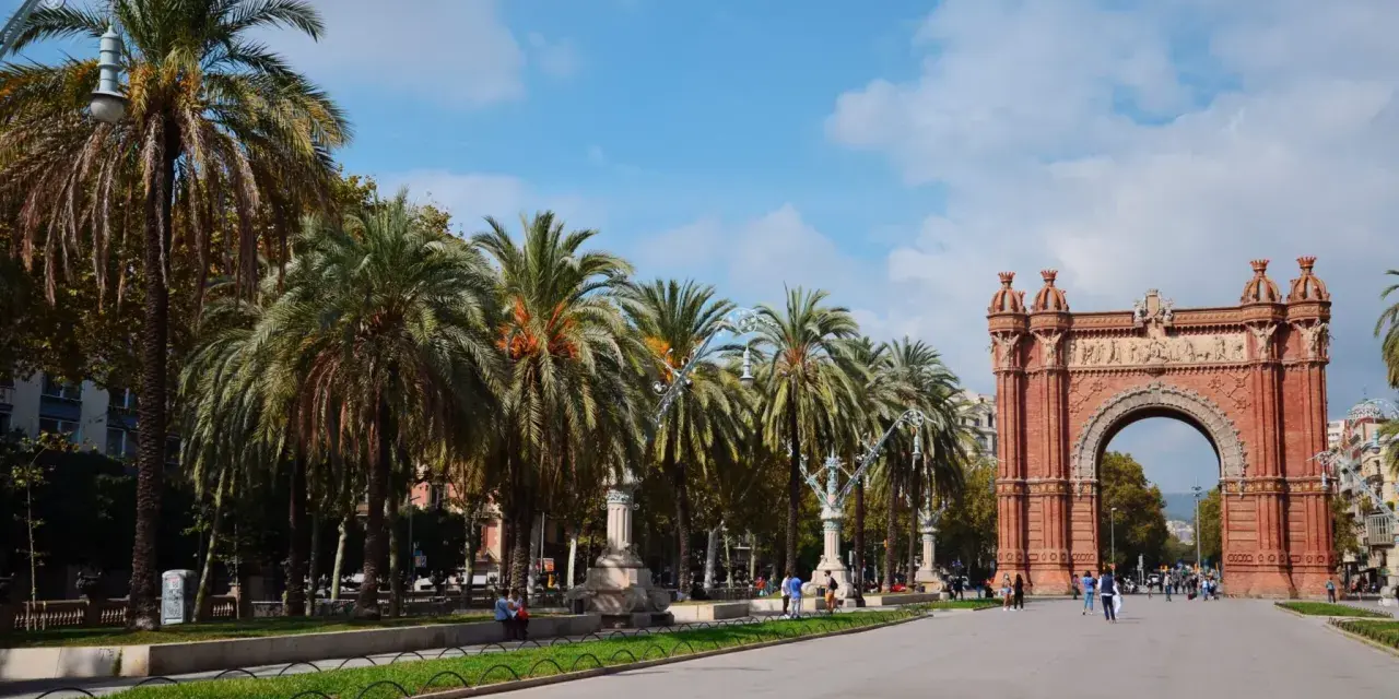 Łuk Triumfalny w Barcelonie z palmami i błękitnym niebem.