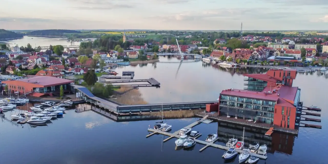 Widok z lotu ptaka na miasteczko nad jeziorem z mariną i nowoczesnymi budynkami.