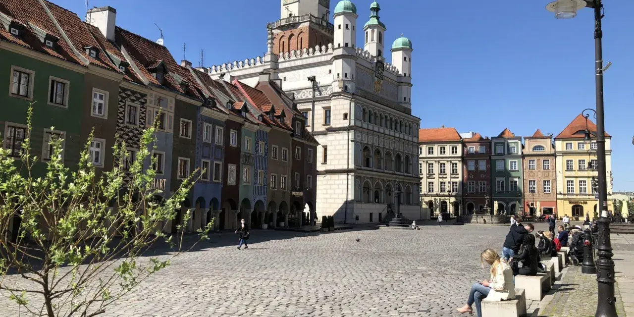 Rynek w Poznaniu z kolorowymi kamienicami i Ratuszem w tle.