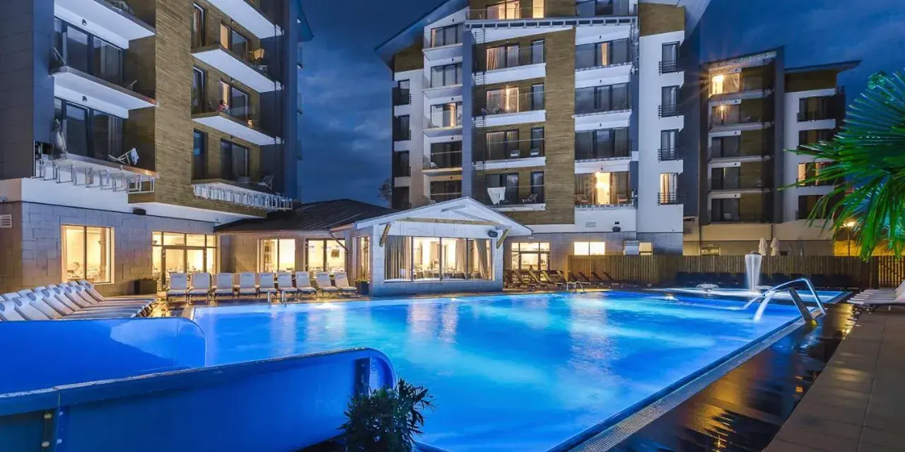 Nowoczesny hotel z basenem i leżakami wieczorem.