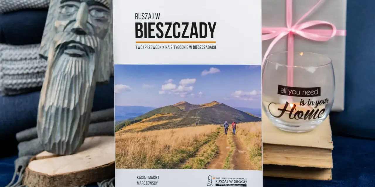 Drewniana rzeźba, książka o Bieszczadach, szklanka z napisem "Home" i prezent.