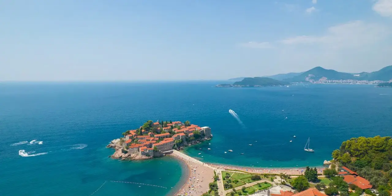 Wyspa Sveti Stefan w Czarnogórze z plażą i turkusowym morzem.