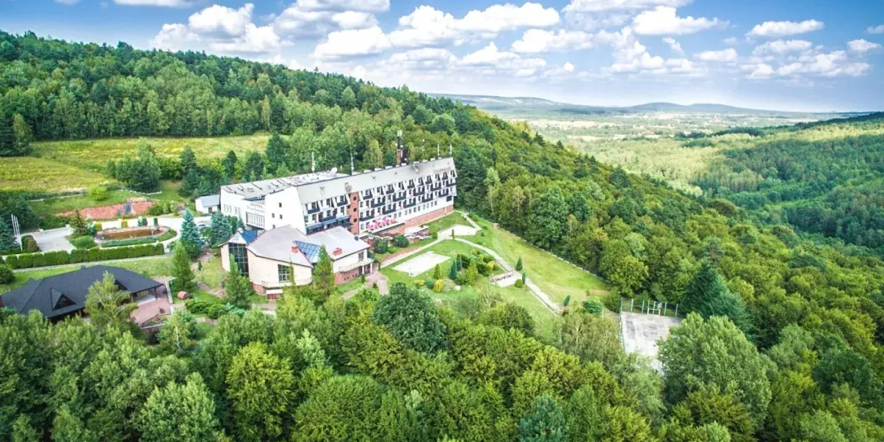 Hotel w otoczeniu zielonych lasów Gór Świętokrzyskich, z widokiem na dolinę.