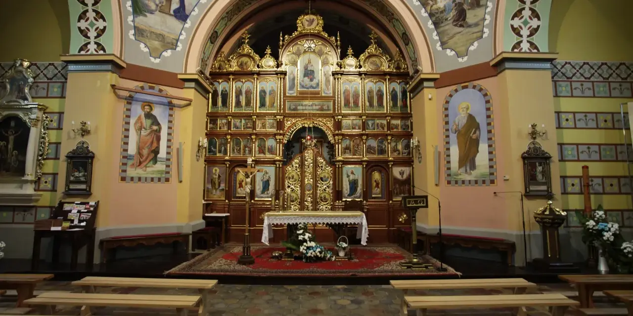 Wnętrze kościoła z ikonostasem, ołtarzem i ławkami.