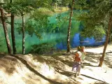 Dwie dziewczynki w słomkowych kapeluszach idą ścieżką nad turkusowym jeziorem.