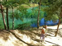 Dwie dziewczynki w słomkowych kapeluszach idą ścieżką nad turkusowym jeziorem.