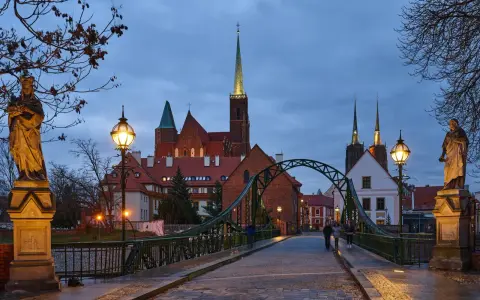 Most wrocławskiej katedry o zmierzchu z widokiem na wieże kościelne i rzeźby.