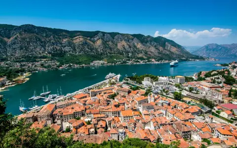 Widok na zabytkowe miasto Kotor w Czarnogórze z zatoką i górami w tle.