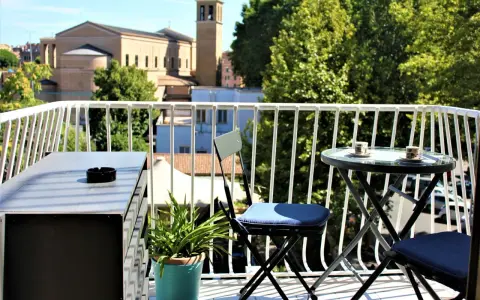 Balkon z widokiem na rzymskie budynki i zieleń, stolik z kawą.