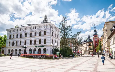Rynek w Cieplicach Śląskich-Zdroju z zabytkowymi kamienicami i wieżą kościelną.