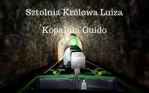 Osoba w kasku jedzie kolejką podziemną w sztolni.
