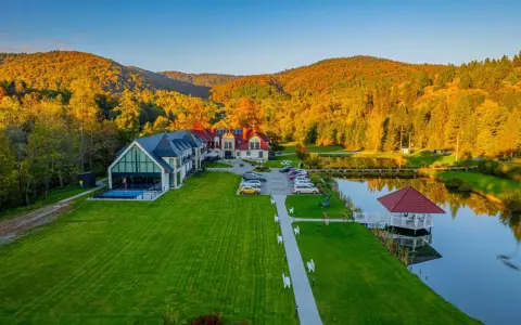 Hotel SPA w Bieszczadach otoczony jesiennym lasem, z basenem i stawem.