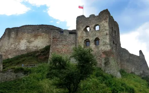 Ruiny zamku w Czorsztynie na wzgórzu, z polską flagą na wieży.