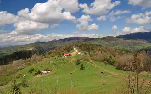 Widok na Palenicę Szczawnica z budynkami, trasami i górami w tle.