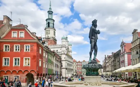Pomnik króla na Rynku w Poznaniu, w tle kolorowe kamienice i ratusz.