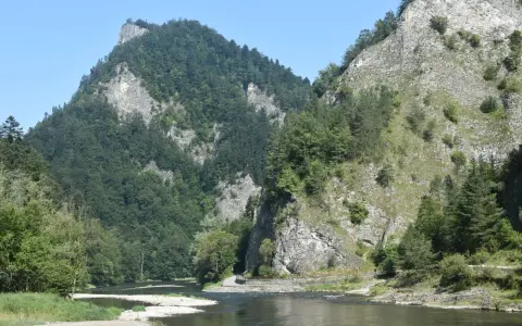 Rzeka Dunajec w przełomie, otoczona stromymi, zalesionymi górami i skalnymi zboczami.