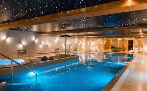 Basen w hotelu SPA z podświetlanym sufitem imitującym gwiazdy i błękitną wodą.