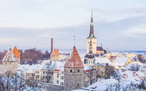 Widok na zasypane śniegiem wieże i dachy Starego Miasta w Tallinnie.