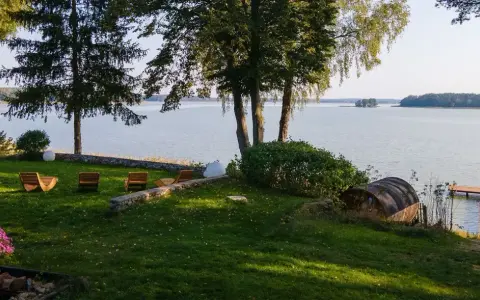 Taras z leżakami nad jeziorem, z widokiem na las i pomost.
