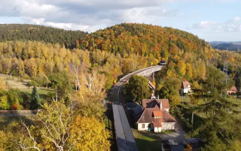 Widok z lotu ptaka na jesienne Góry Sowie z mostem kolejowym i domami.
