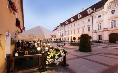 Taras restauracji z parasolami i kwiatami na tle zabytkowej kamienicy w Cieplicach.