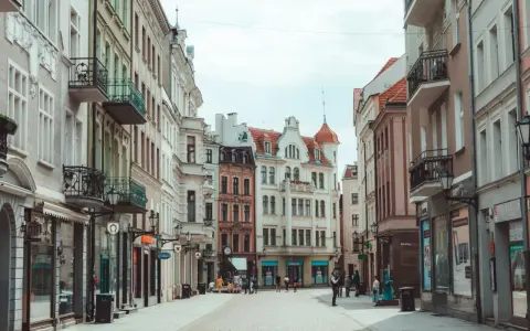 Ulica z kolorowymi kamienicami i ludźmi spacerującymi po bruku.