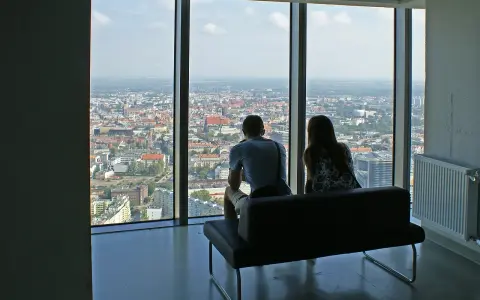 Para siedząca na kanapie, patrząca na panoramę Wrocławia z wysokości.