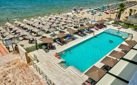Widok z lotu ptaka na hotelowy basen i plażę z leżakami i parasolami w Durrës, Albania.