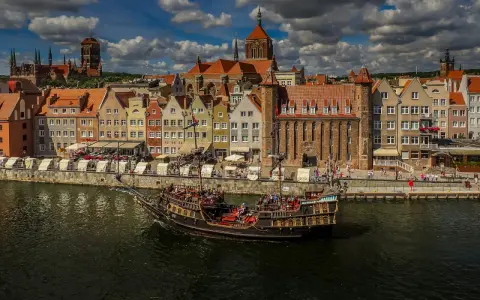 Żaglowiec na Motławie przed kolorowymi kamieniczkami w Gdańsku.