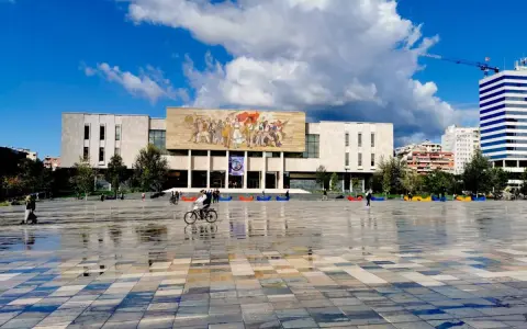 Plac w Tiranie z budynkiem Narodowego Muzeum Historii i kolorowymi pufami.