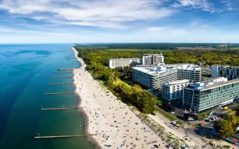 Widok z lotu ptaka na plażę nad Bałtykiem z hotelami i turystami.