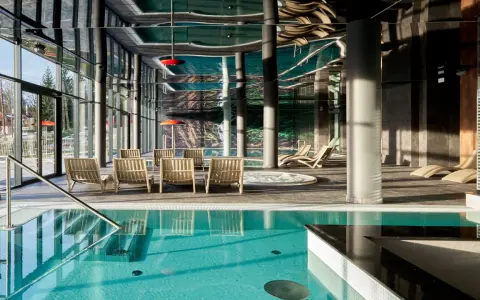 Basen z turkusową wodą i leżakami w nowoczesnym hotelowym spa.