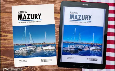 Okładka przewodnika po Mazurach z widokiem na żaglówki przy pomoście.