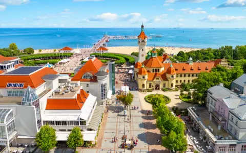 Widok z lotu ptaka na nadmorską miejscowość z plażą, molo i zabytkowymi budynkami.