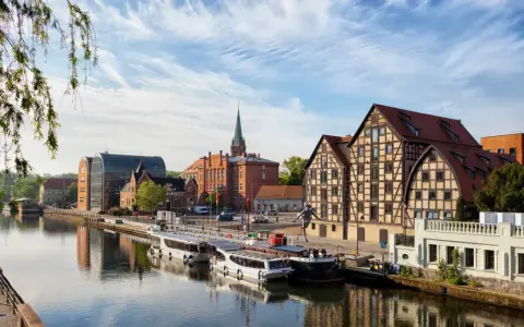 Bydgoszcz: rzeka, statki, zabytkowe kamienice i nowoczesna architektura.