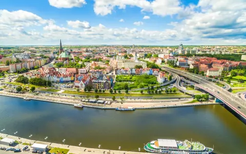 Widok z lotu ptaka na Szczecin z rzeką, nabrzeżem, statkami i mostem.