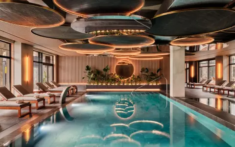 Nowoczesny basen w hotelu SPA z leżakami i roślinnością.