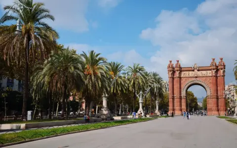 Łuk Triumfalny w Barcelonie z palmami i błękitnym niebem.