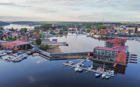 Widok z lotu ptaka na miasteczko nad jeziorem z mariną i nowoczesnymi budynkami.