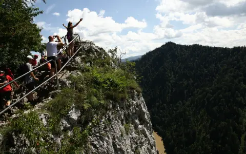 Grupa turystów na skalistym szczycie z widokiem na Pieniny i Dunajec.