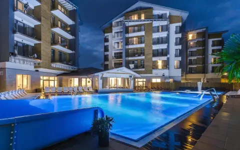 Nowoczesny hotel z basenem i leżakami wieczorem.