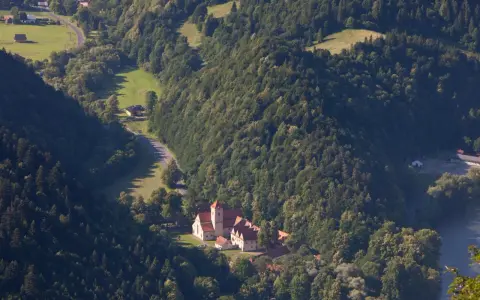 Widok z lotu ptaka na Czerwony Klasztor otoczony zielonymi wzgórzami i lasami.