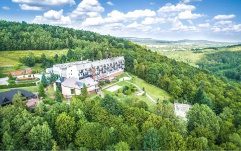 Hotel w otoczeniu zielonych lasów Gór Świętokrzyskich, z widokiem na dolinę.