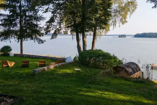 Taras z leżakami nad jeziorem, z widokiem na las i pomost.