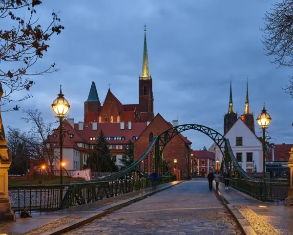 Most wrocławskiej katedry o zmierzchu z widokiem na wieże kościelne i rzeźby.