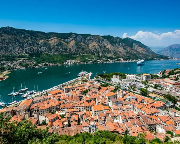 Widok na zabytkowe miasto Kotor w Czarnogórze z zatoką i górami w tle.