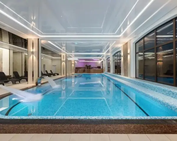 Nowoczesny basen w hotelu spa z wodospadem i leżakami.